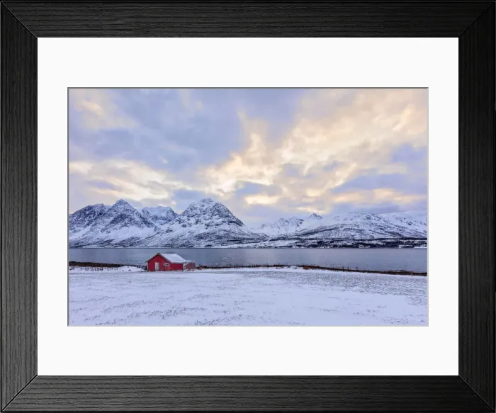 Framed Print : Typical Rorbu in the snowy landscape surrounded by the frozen sea and high peaks Svensby