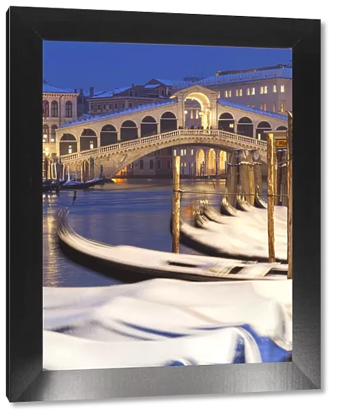 Rialto Bridge with snow-covered gondolas at dusk after a snowfall, Grand Canal, Venice