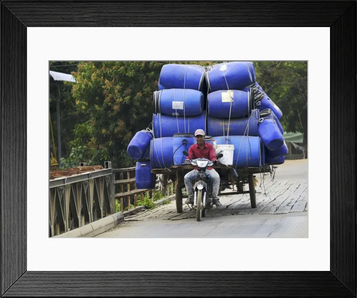 Framed Print : Asia, South East Asia, Cambodia, motorbike rider with a heavy load crossing a bridge