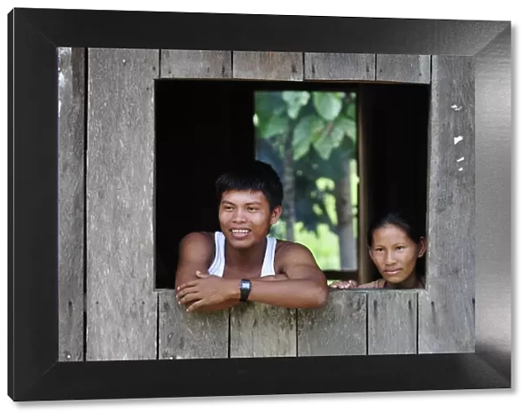 Couple looking out of window in the Amacayon Indian Village, Amazon river, Puerto Narino