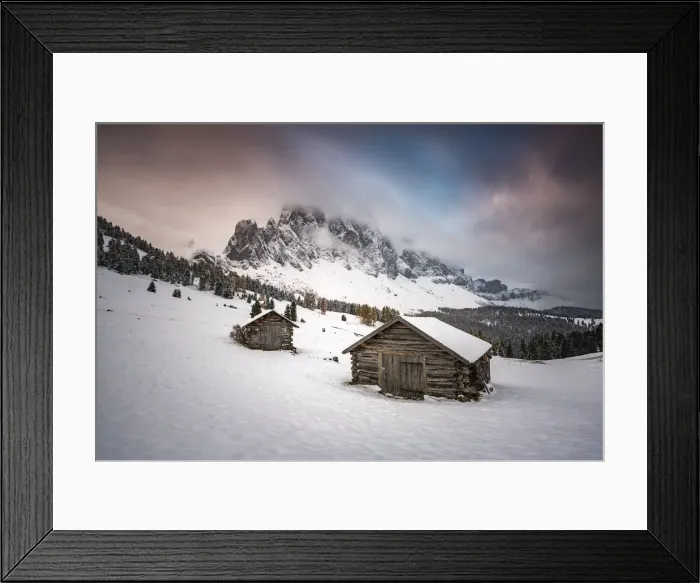 Framed Print : Winter scenery with two wooden lodges and Odle Dolomites covered in snow. Malga Gampen