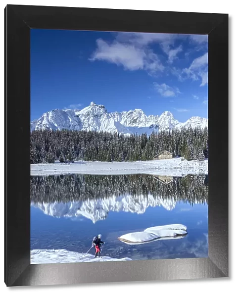 Hiker proceeds on the shore of PalA'A¹ Lake surrounded by snowy peaks and woods Malenco Valley Valtellina Lombardy Italy Europe