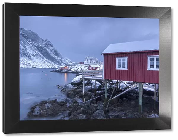 Typical fishermen houses called rorbu in the snowy landscape at dusk Nusfjord Nordland