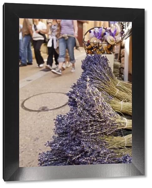Rousillion; France. People walking down a street with lavender for sale in the foreground