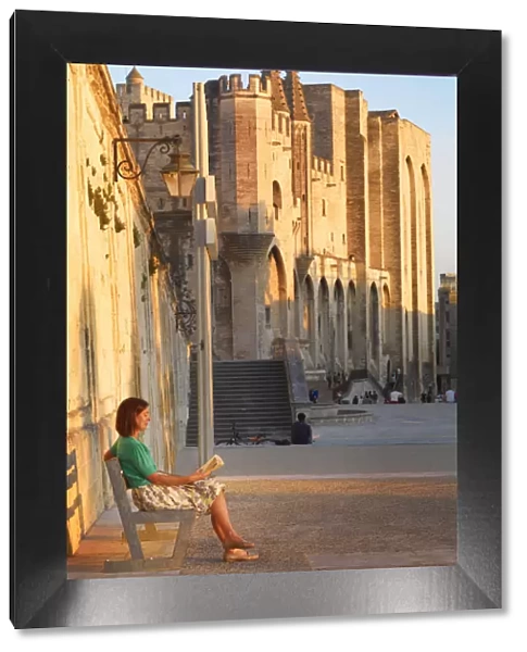 France, Provence, Avignon, Palais de Papes, Woman reading book on bench MR
