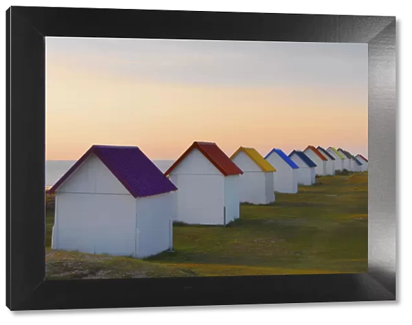 France, Normandy, Gouville Sur Mer, colourful beach huts, two people standing by sea