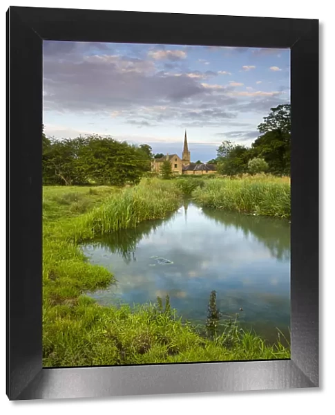 Burford Church spire reflected in the River Windrush watermeadows, Burford, The Cotswolds