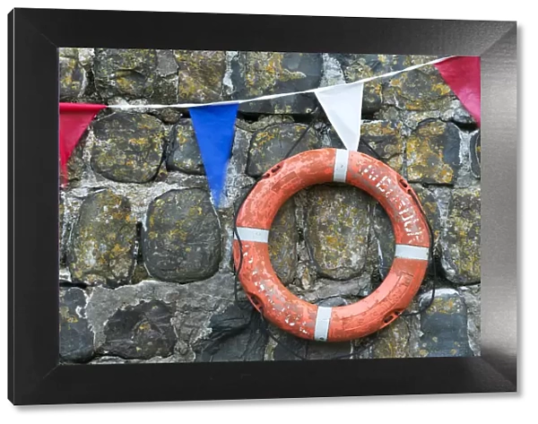 Life ring and bunting on the old harbour wall at Clovelly, Devon, England. Summer