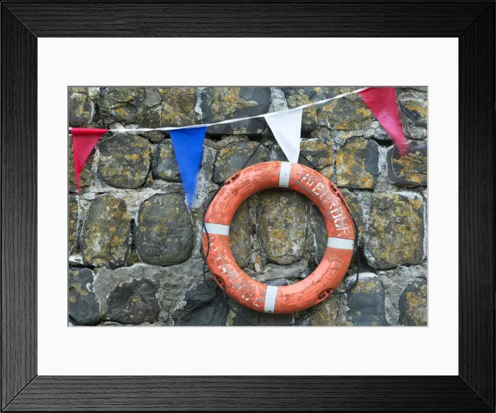 Framed Print : Life ring and bunting on the old harbour wall at Clovelly, Devon, England. Summer Framed Print : Life ring and bunting on the old harbour wall at Clovelly, Devon, England. Summer