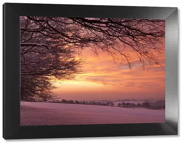 Spectacular dawn sky above snow covered countryside, Exmoor, Somerset, England. Winter