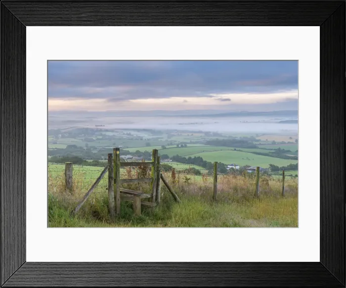 Framed Print : Footpath and stile through farmland with mist covered countryside beyond, Devon, England Framed Print : Footpath and stile through farmland with mist covered countryside beyond, Devon, England