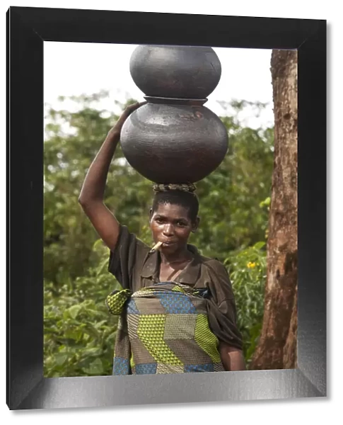 Burundi. A woman uses traditional pots to transport her goods to market