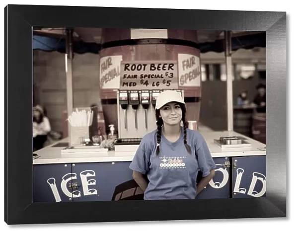 A young girl selling root beer at a midway concession at the Calgary Stampede, Canada