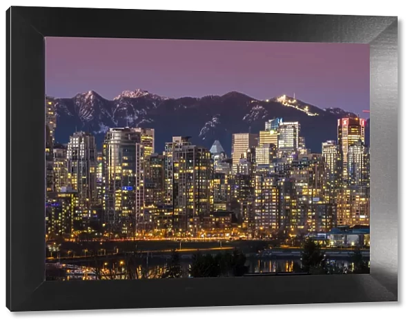 Downtown skyline with snowy mountains behind at dusk, Vancouver, British Columbia, Canada