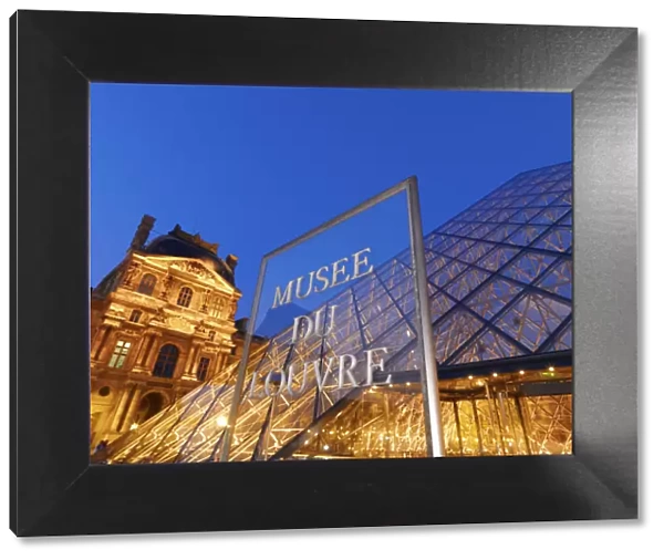 France, Paris, The Louvre, museum, pyramid and sign illuminated at night