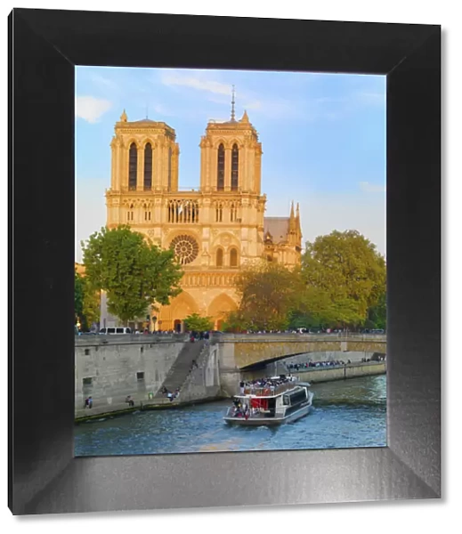 France, Paris, Notre Dame Cathedral and tourist boat on River Seine at sunset