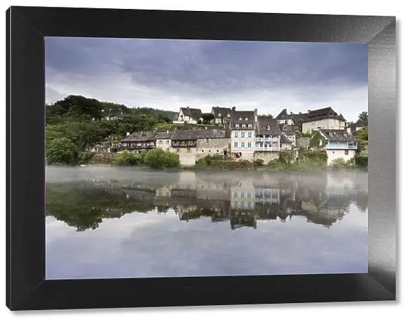 France, Correze, Argentat, Old houses and a layer of mist are reflected in the Dordogne