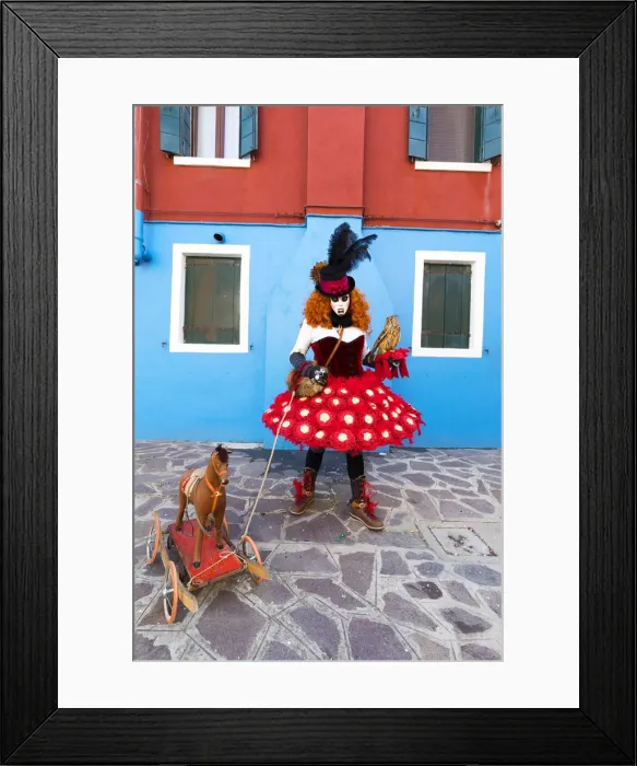 Framed Print : A woman in a colourful costume poses with a toy dog in a street on Burano Island during Framed Print : A woman in a colourful costume poses with a toy dog in a street on Burano Island during