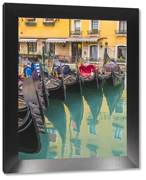 Venice, Veneto, Italy. Colorful moored gondolas reflecting in the water