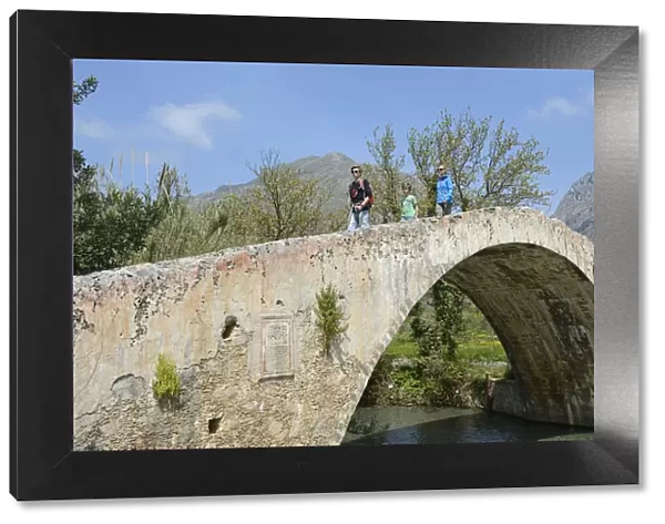 Family moves over the arch bridge over the River Megalopotamos the Preveli, Crete