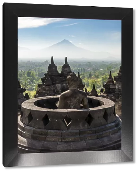 Buddha statue with Mount Merapi in the background, Candi Borobudur buddhist temple