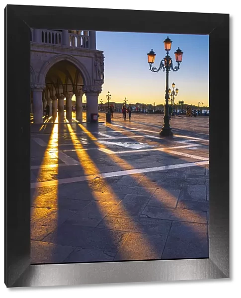 St Mark square, Venice, Veneto, Italy. Sun rays at sunrise through the arches of Palazzo