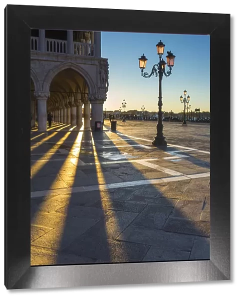 St Mark square, Venice, Veneto, Italy. Sun rays at sunrise through the arches of Palazzo