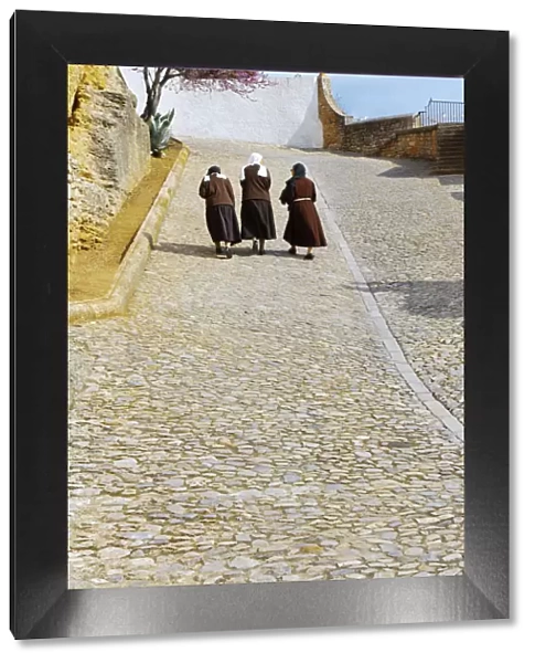 Spain, Andalucia, Malaga Province, Ronda, Three nuns walking up cobbled street