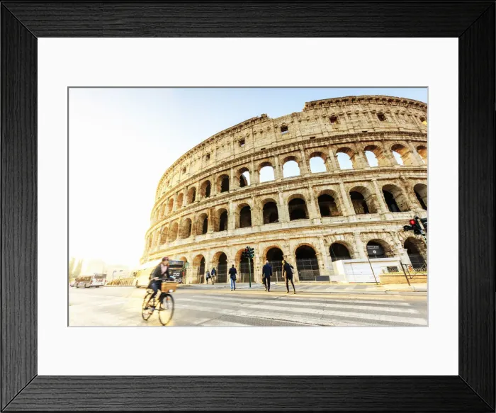 Framed Print : Italy, Rome, a woman riding a bike Colosseum and Roman Forum at sunrise