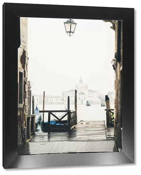 Venice, Veneto, Italy. Pier on the waterfront in the mist and St Mary Of The Presentation