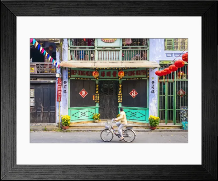 Framed Print : A woman rides a bicycle past buildings in Hoi An Ancient Town, Hoi An, Quang Nam Province Framed Print : A woman rides a bicycle past buildings in Hoi An Ancient Town, Hoi An, Quang Nam Province