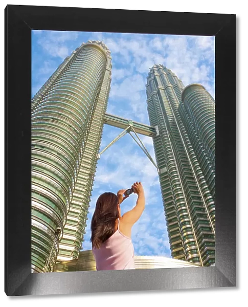 Malaysia, Kuala Lumpur, Petronas Towers, Woman photographing towers MR
