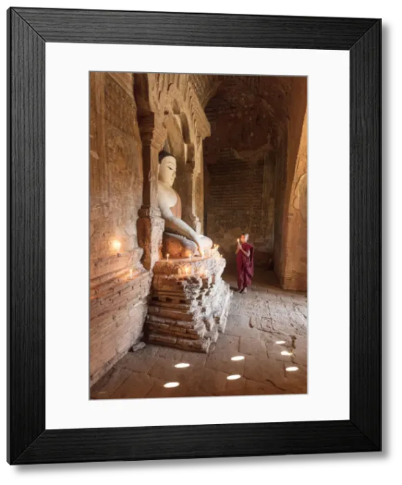 Framed Print : Young Buddhist monk prays in front of a statue of Buddha in a temple in Bagan, Myanmar Framed Print : Young Buddhist monk prays in front of a statue of Buddha in a temple in Bagan, Myanmar