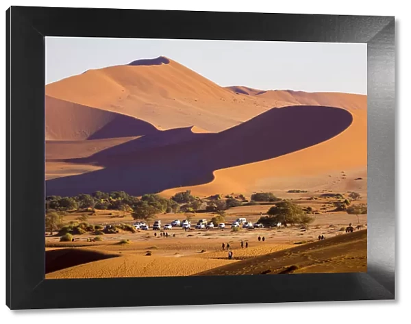 Africa, Namibia, Namib Desert, Sossusvlei, dunes at sunrise with 4x4 offroad cars