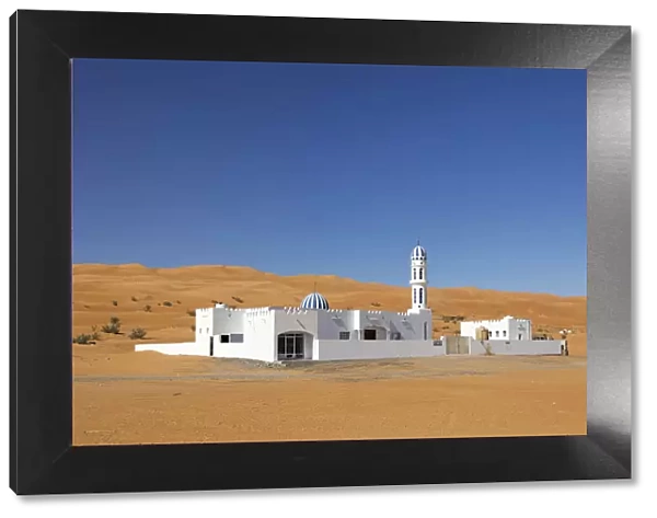 A colourful mosque stands in front of sand dunes at the edge of the desert, Wahiba sands