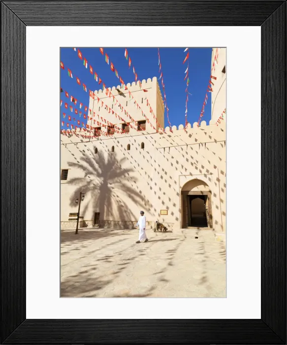 Framed Print : An Omani man walks past Bahla Fort decorated to celebrate the birthday of Sultan Qaboos Framed Print : An Omani man walks past Bahla Fort decorated to celebrate the birthday of Sultan Qaboos