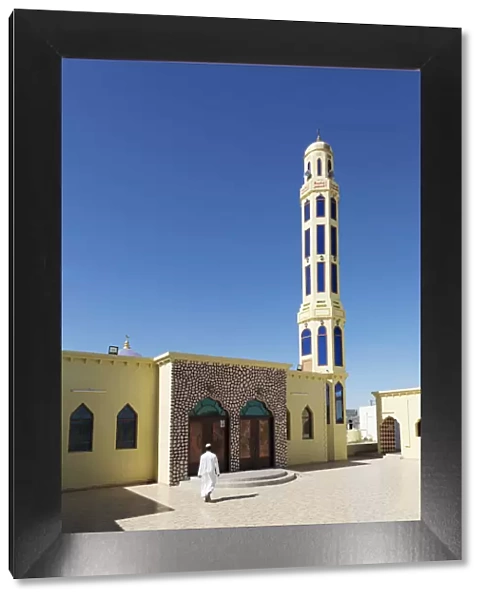 A mullah walks into a colourful mosque for the call to prayer, Nizwa, Ad Dakhiliyah