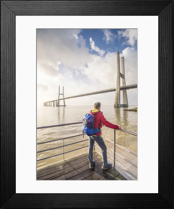 Framed Print : Lisbon, Portugal. Man with backback watching the Vasco Da Gama bridge at sunrise
