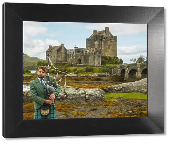 UK, Scotland, Highlands, Dornie, Man in Highland Dress playing bigpipe in front of