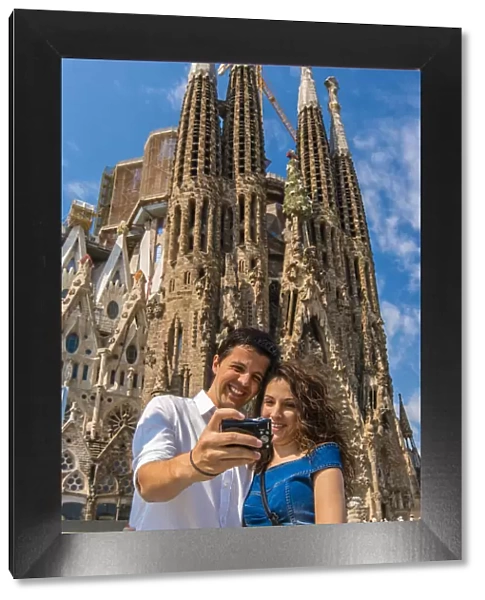 Caucasian young couple taking photo of themselves in front of Sagrada Familia church