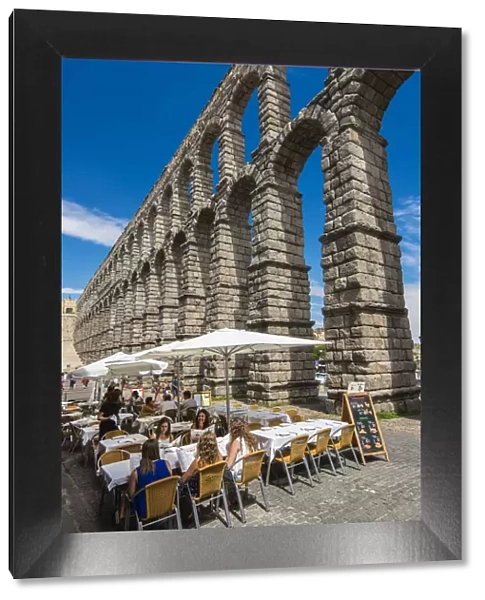 Outdoor restaurant with Roman aqueduct bridge behind, Segovia, Castile and Leon, Spain