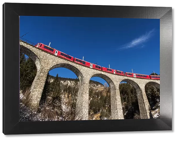 The famous red train of Albula mountain railway while passing on the Landwasser viaduct