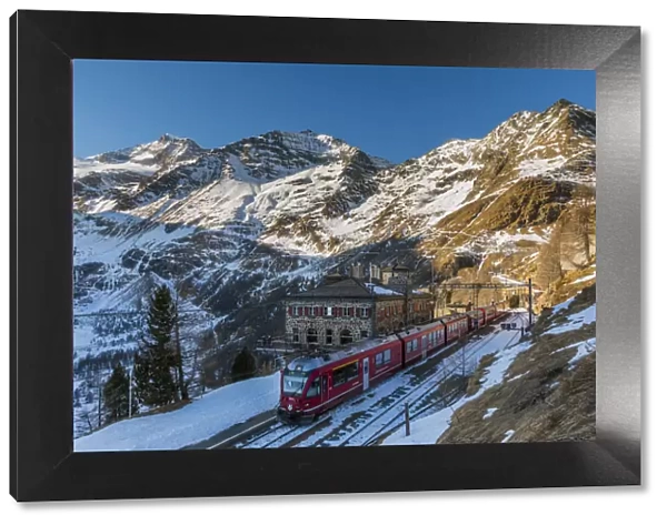 The famous Bernina Express red train at Alp Grum station in a scenic winter day