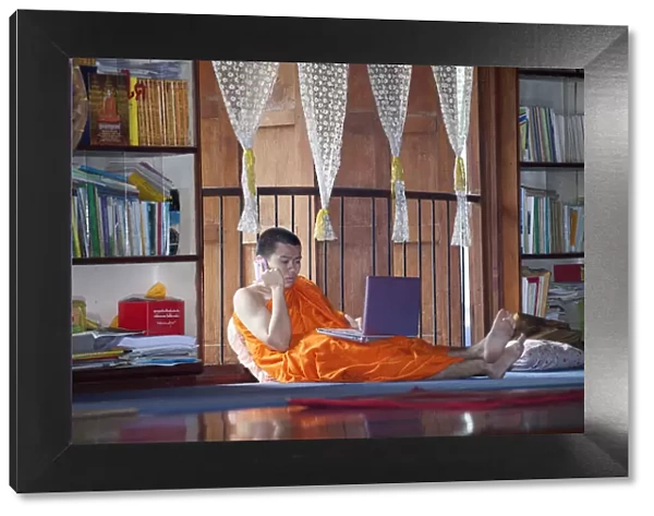 South East Asia, Thailand, Buddhist monk using a lap top and a mobile phone