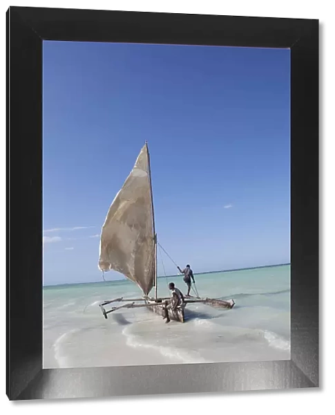 Two men sailing a boat in the surf off Zanzibar in East Africa
