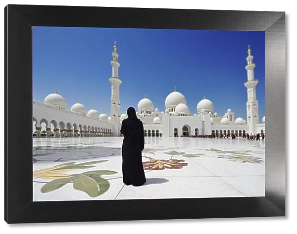 Woman in a black burkha stands in front of Sheikh Zayed Mosque, Abu Dhabi, United