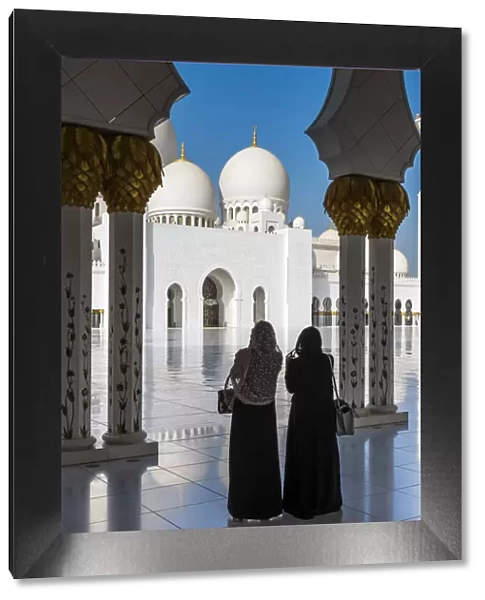 Two Middle Eastern women traditionally dressed watching the Sheikh Zayed Mosque, Abu