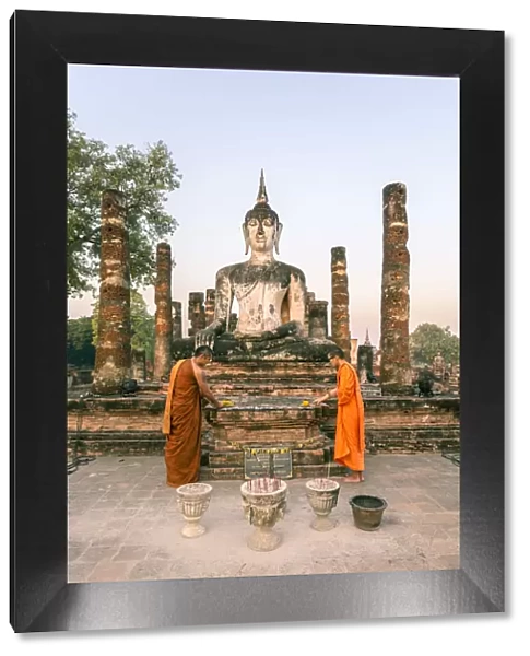 Thailand, Sukhothai Historical Park. Two buddhist monks offering flowers at Wat Mahathat