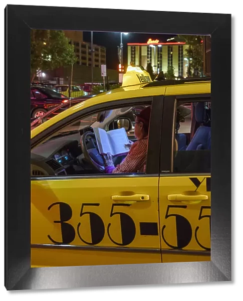 USA, Nevada, Reno, woman cabbie reading in cab at night