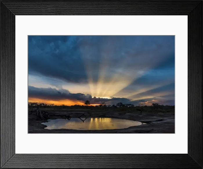 Framed Print : Africa, Zimbabwe, Hwange National park. View across a waterhole at sunbeams bursting